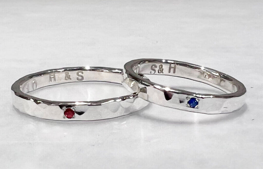 一对蓝色蓝宝石和石榴石扣在一起的银戒指。
